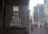 Sign for The Wall Street Journal on a building in a busy city street