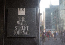 Sign for The Wall Street Journal on a building in a busy city street