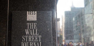 Sign for The Wall Street Journal on a building in a busy city street