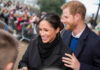 A smiling couple interacting with a crowd during a public event