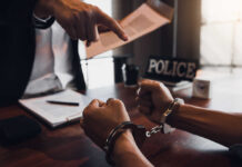 A person in handcuffs being confronted by a police officer