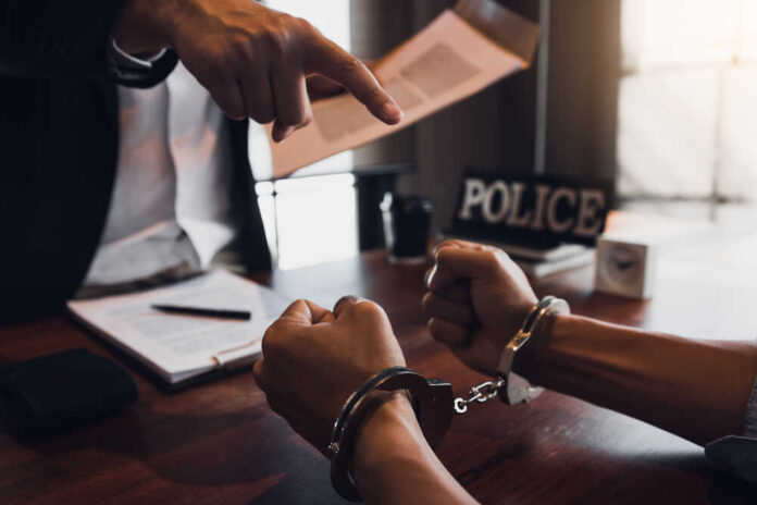 A person in handcuffs being confronted by a police officer