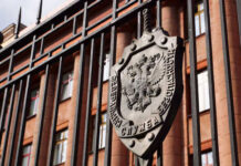 Close-up of a metal emblem on a gate in front of a government building