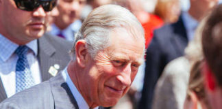 A smiling man in formal attire interacting with a crowd