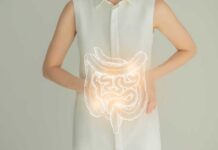 Woman in a white shirt holding her stomach with a glowing illustration of the digestive system