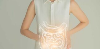 Woman in a white shirt holding her stomach with a glowing illustration of the digestive system