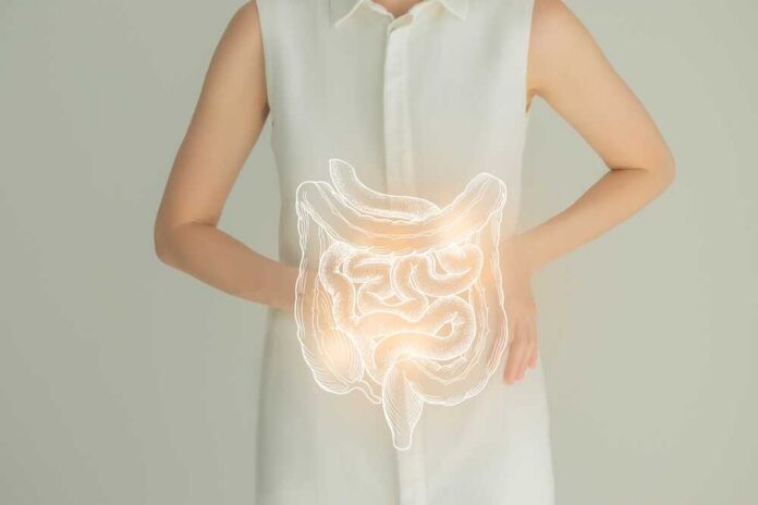 Woman in a white shirt holding her stomach with a glowing illustration of the digestive system