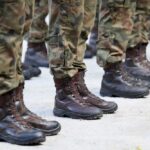 Row of soldiers in camouflage uniforms standing at attention with military boots