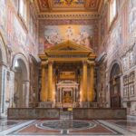Interior view of a grand religious building with ornate frescoes and a central altar