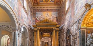 Interior view of a grand religious building with ornate frescoes and a central altar