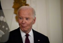 A man in a pinstripe suit smiling in an indoor setting
