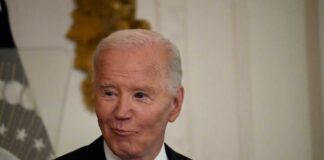A man in a pinstripe suit smiling in an indoor setting