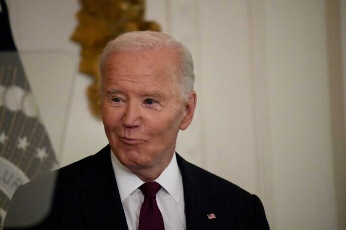 A man in a pinstripe suit smiling in an indoor setting