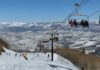 Skiers on a snowy slope with a chairlift in the background