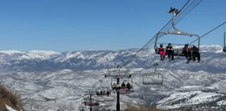 Skiers on a snowy slope with a chairlift in the background