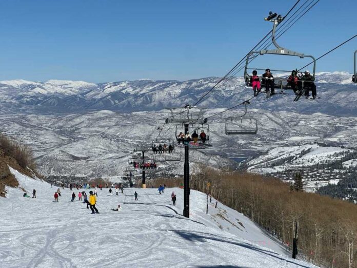 Skiers on a snowy slope with a chairlift in the background