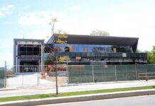 A partially constructed modern building with a glass facade and construction equipment