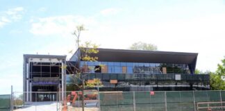 A partially constructed modern building with a glass facade and construction equipment