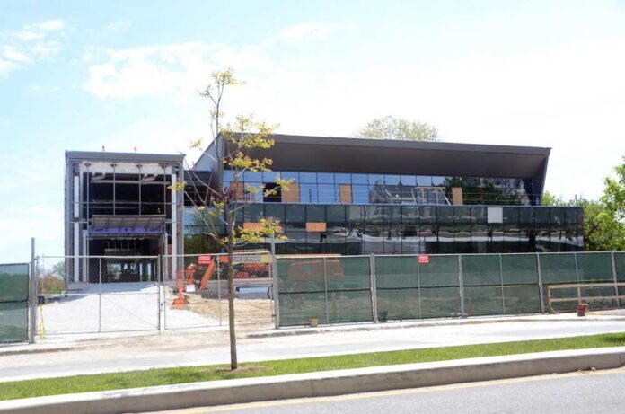 A partially constructed modern building with a glass facade and construction equipment