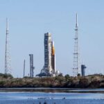 Rocket on the launch pad surrounded by communication towers and water