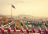 View of Iranian flags with a city and mountains in the background