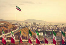 View of Iranian flags with a city and mountains in the background