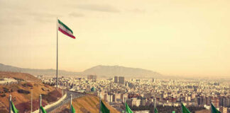 View of Iranian flags with a city and mountains in the background