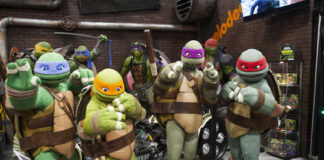 Four characters in turtle costumes posing at a convention