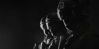 Silhouetted tactical team members in uniform with weapons