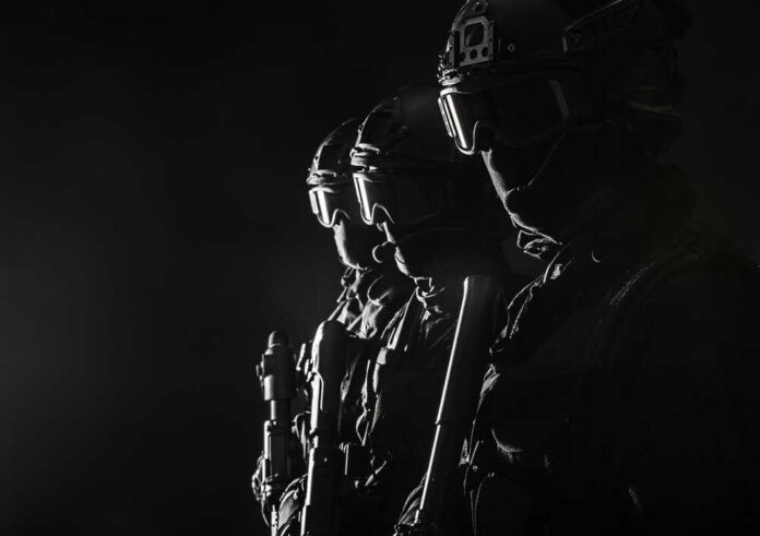 Silhouetted tactical team members in uniform with weapons