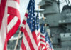Row of American flags in front of a naval ship