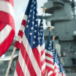 Row of American flags in front of a naval ship