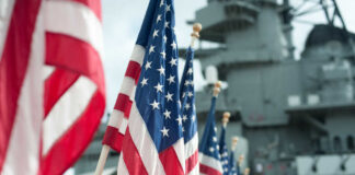 Row of American flags in front of a naval ship
