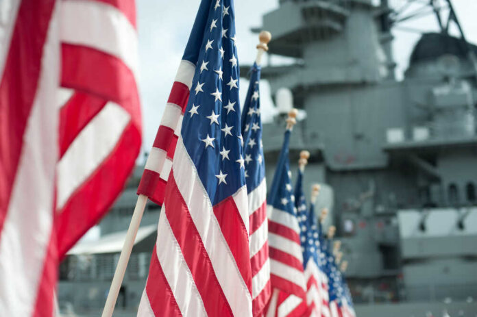 Row of American flags in front of a naval ship