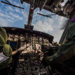 Interior view of a helicopter cockpit with pilots operating controls