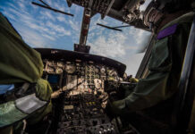 Interior view of a helicopter cockpit with pilots operating controls