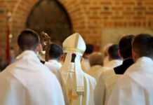 Clerics in white robes facing altar in church