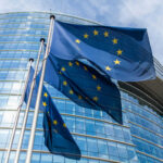 Alliance Fractures: EU Challenges US Actions European Union flags outside modern glass building