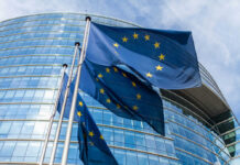 Alliance Fractures: EU Challenges US Actions European Union flags outside modern glass building
