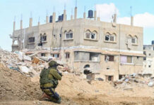 Soldier crouching near damaged building in urban area