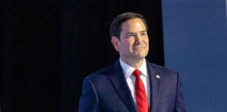 Man in suit with red tie on stage