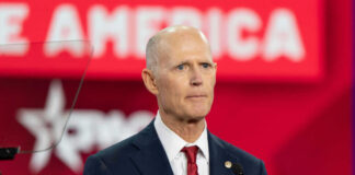 Bald man in suit speaking at a podium