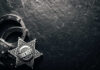 Sheriff badge and handcuffs on dark stone background