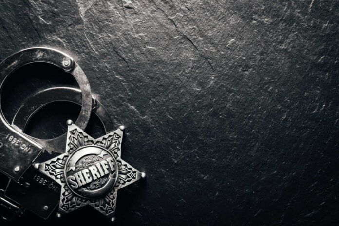 Sheriff badge and handcuffs on dark stone background