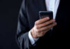 A person in a suit holding a smartphone