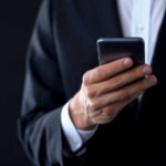 A person in a suit holding a smartphone