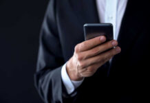 A person in a suit holding a smartphone