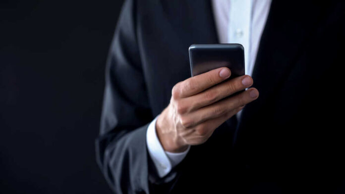 A person in a suit holding a smartphone