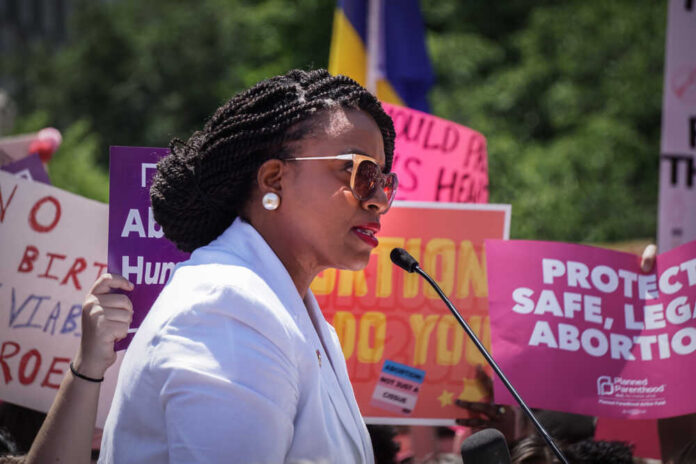 Washington,,Dc,-,May,21,,2019:,Congresswoman,Ayanna,Pressley,Speaks A woman speaking at a protest with signs advocating for abortion rights in the background