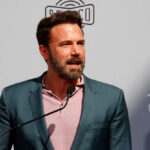 A man in a suit speaking at a podium during a public event